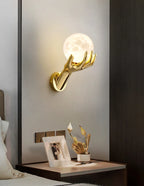 Golden Hand Wall Lamp — Moon shade mounted above a nightstand beside a bed