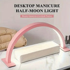 Half Moon Nail Lamp pink arch above a white manicure hand rest, with nail polish bottles beside it.