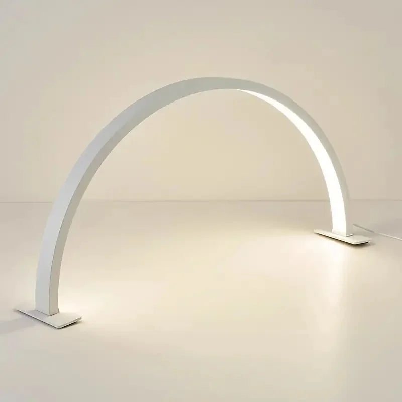 Half Moon Nail Lamp white arch on a pale tabletop with the power cable extending from its right base.