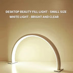 Half Moon Nail Lamp white front view with the illuminated arch casting light onto a desktop.