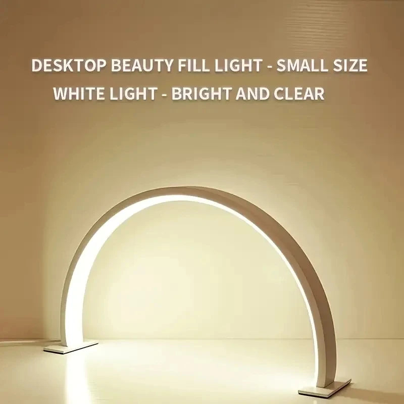 Half Moon Nail Lamp white front view with the illuminated arch casting light onto a desktop.