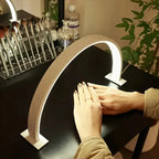 Half Moon Nail Lamp in white above manicured hands on a black beauty desk beside a brush organiser.