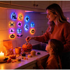 Halloween 3D Wall Lights glowing above a kitchen counter with cupcakes, candy and a pumpkin-shaped container.