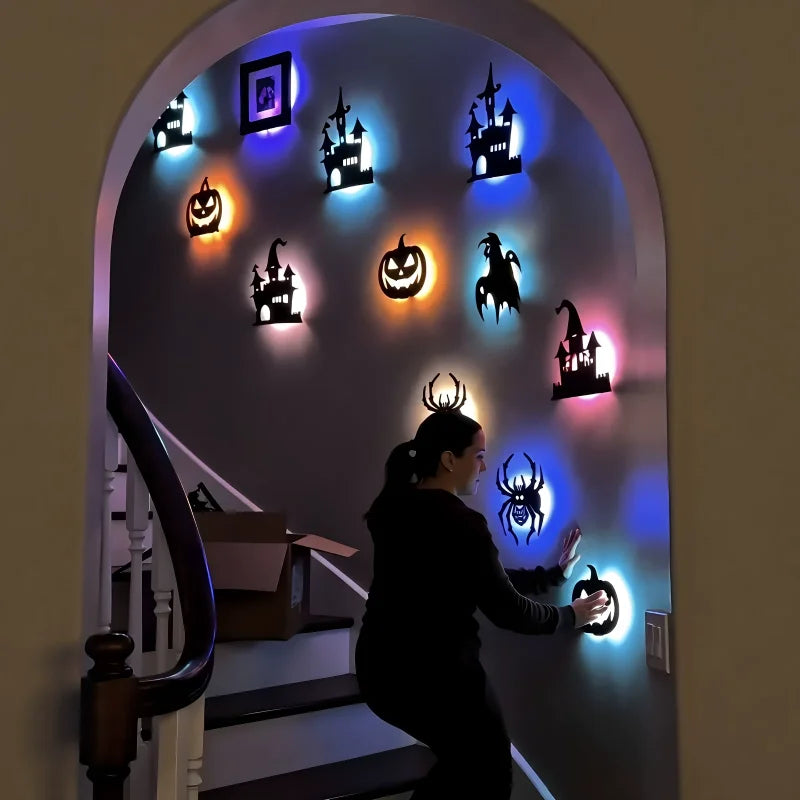 Halloween 3D Wall Lights lining the staircase wall with glowing castles, pumpkins and spiders around a person.