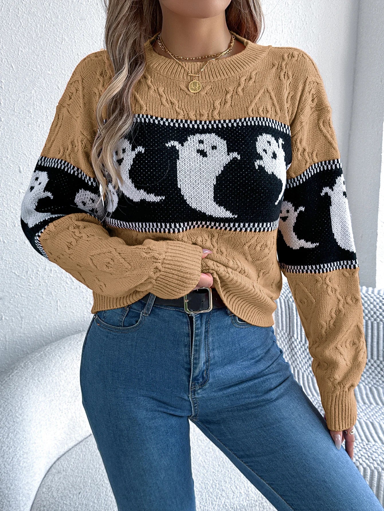 Halloween Ghost Knit Sweater khaki colorway styled with blue jeans and hands gathered at the waist