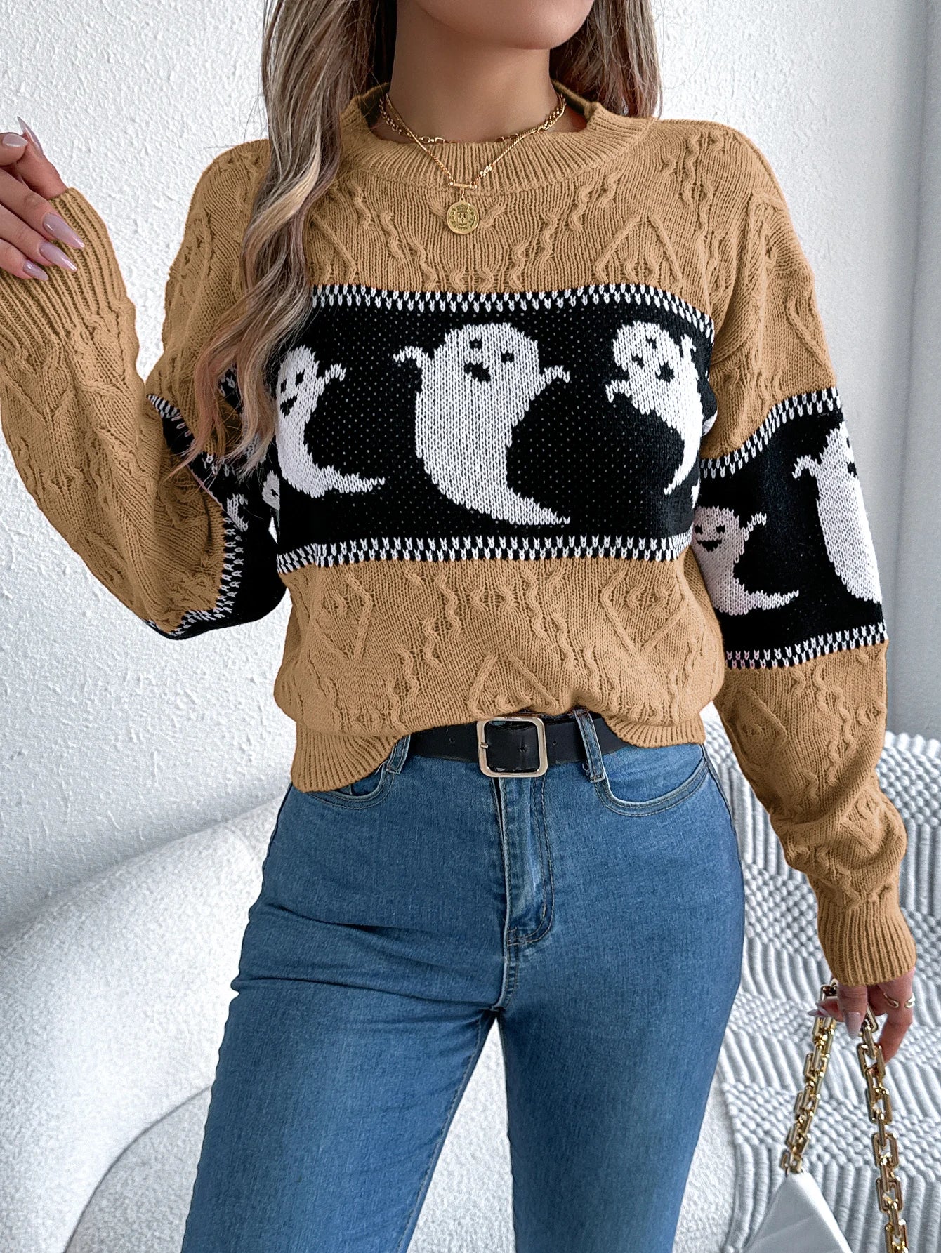 Halloween Ghost Knit Sweater in khaki styled from the front with a raised sleeve and small handbag