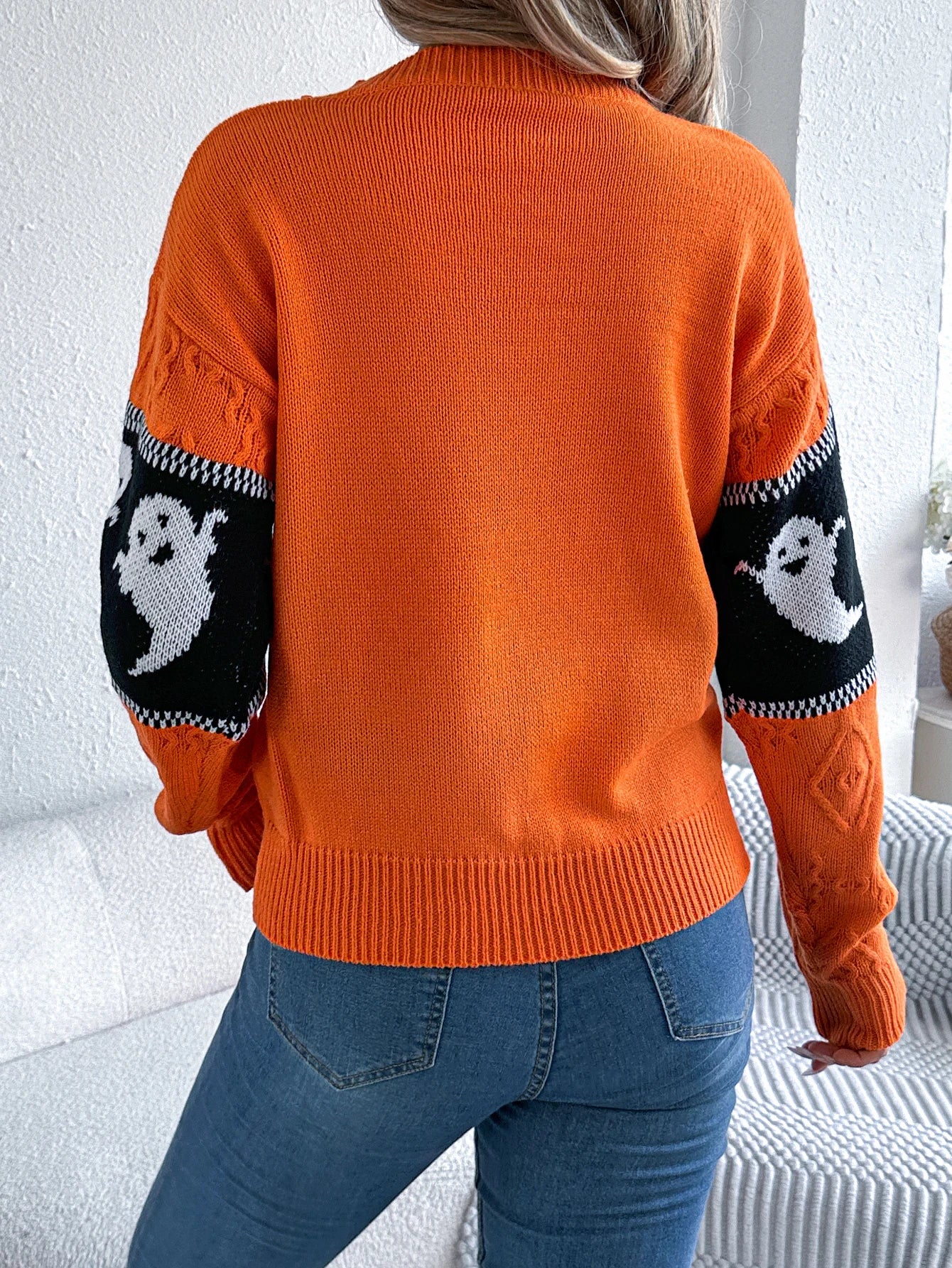 Halloween Ghost Knit Sweater orange back view showing plain knit body and ghost-pattern sleeve stripes