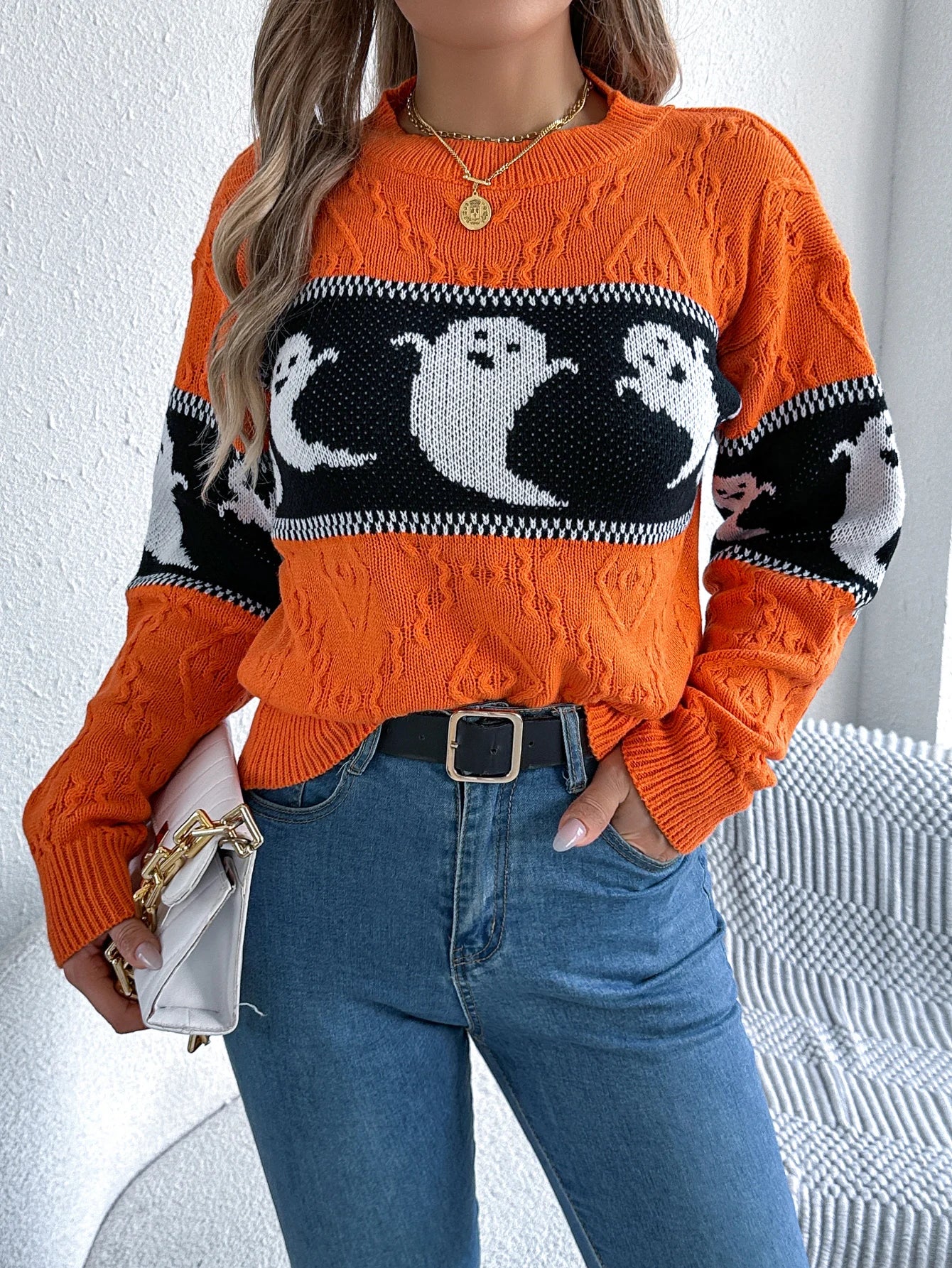 Halloween Ghost Knit Sweater orange colorway styled from the front with blue jeans and a light handbag