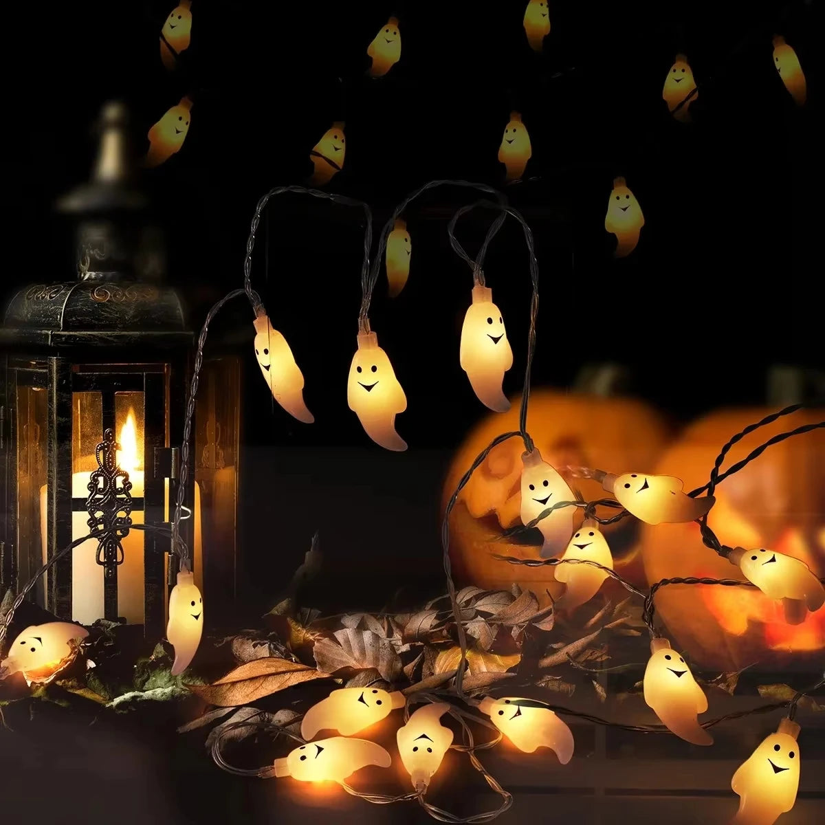 Halloween Ghost String Lights draped around a lantern, pumpkins and autumn leaves on a tabletop.