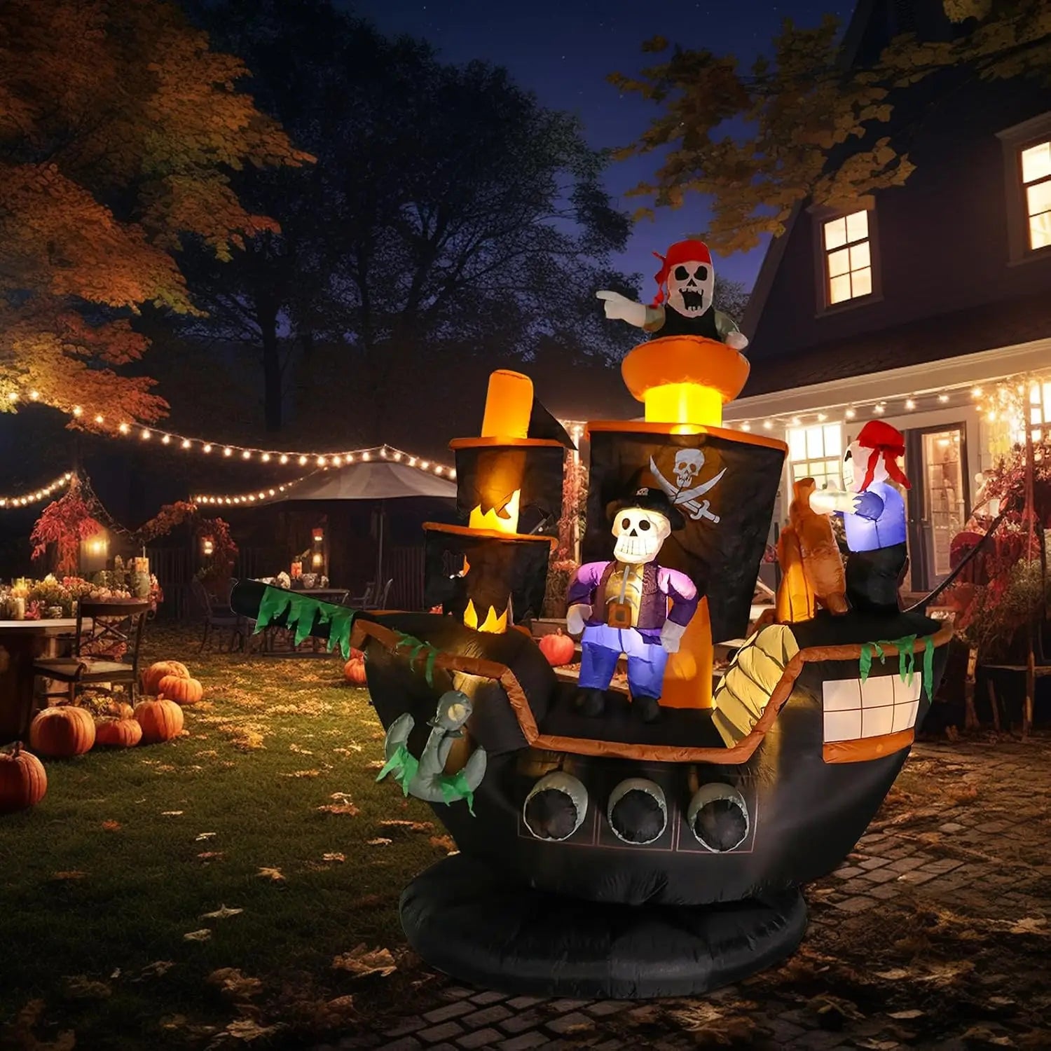 Halloween pirate ship inflatable glowing beside a home in a decorated front-yard nighttime scene