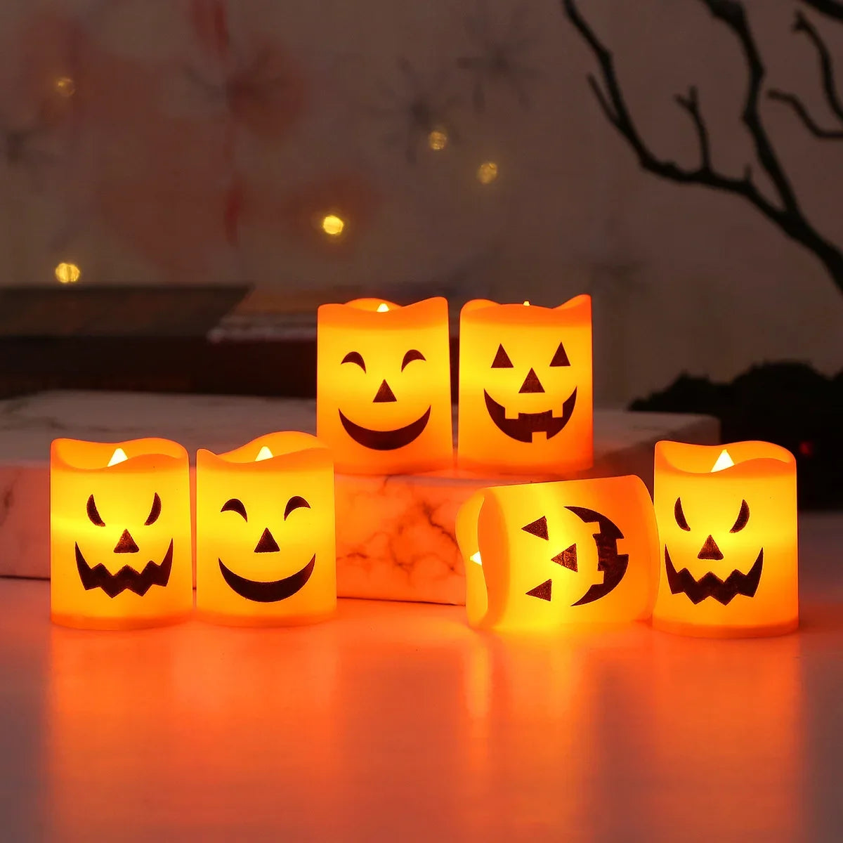 Halloween Pumpkin LED Candle Set: six glowing candles arranged on a table and riser, with one on its side.
