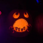 Halloween Pumpkin Teeth Inserts silhouetted along a wide pumpkin mouth glowing orange at night