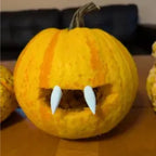 Halloween Pumpkin Teeth Inserts forming a simple two-fang vampire mouth in a yellow pumpkin