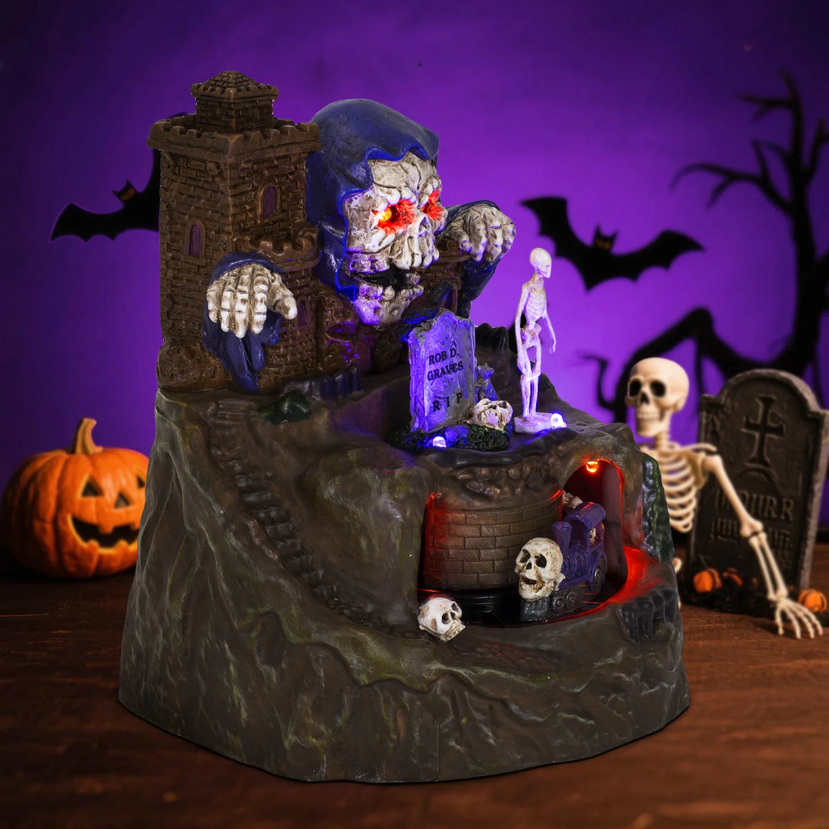 Haunted Halloween Train Village at HighPeak lit from a side angle showing castle tower, steps, skeleton, and train.
