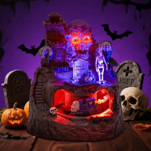 Haunted Halloween Train Village at HighPeak glowing on a tabletop surrounded by pumpkins, skulls, and tombstones.