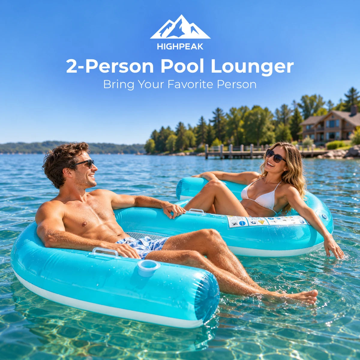 Two people relaxing in bright blue inflatable pool loungers on a sunny lake with trees and houses in the background. White text at the top reads 'HIGHPEAK 2-Person Pool Lounger Bring Your Favorite Person'.
