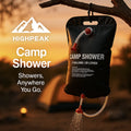 HighPeak Camp Shower black bag hanging from tree branch outdoors with water flowing at sunset campsite