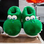 Front view of green crocodile slippers with open plush collars on a wooden surface