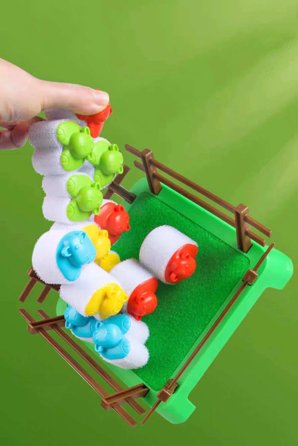 Hand lifting a chain of attached sheep above the game pen