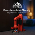 HighPeak Door Jammie McSlammy in red secured under a door with alarm sensor in a dimly lit bedroom setting