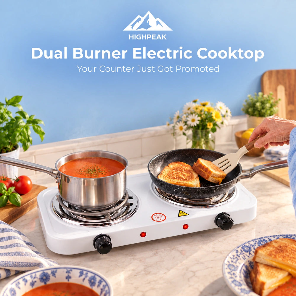 HighPeak dual burner electric cooktop on a kitchen counter with a pot of tomato soup and a frying pan of toasted bread, with a hand flipping the toast. The background shows a blue wall and kitchen decor.
