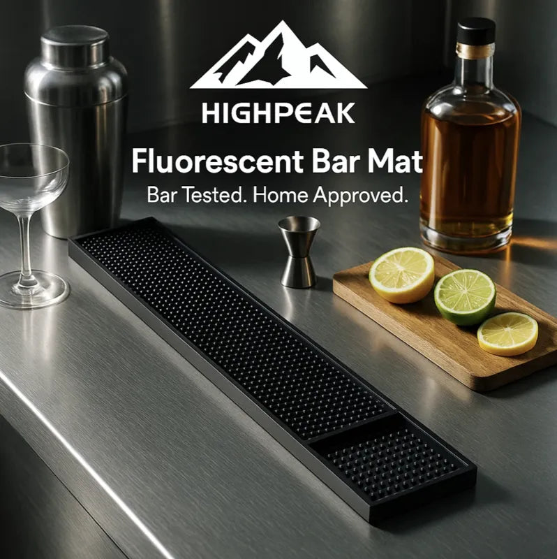 HighPeak Bar Counter Mat in black with fluorescent dots on a stainless steel bar countertop with cocktail tools and sliced citrus.
