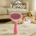 FurPop™ Self Cleaning Pet Brush in pink with ergonomic handle and one-click hair eject, shown on carpet near dog with fur.