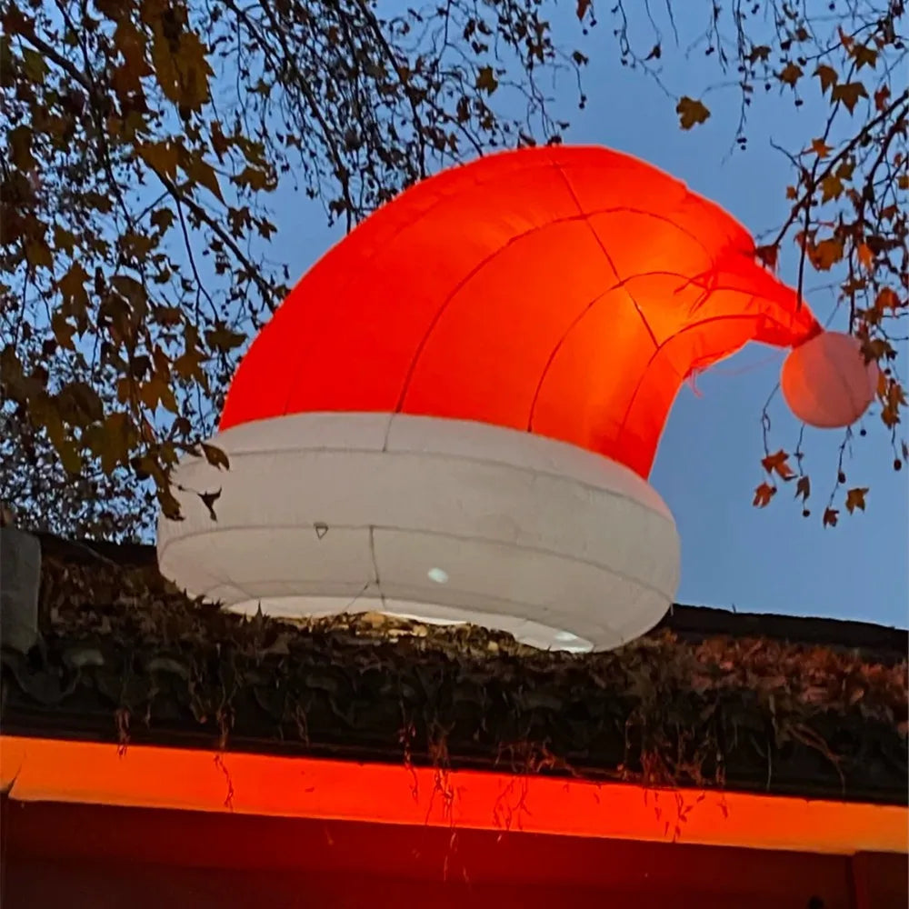 LED Giant Inflatable Santa Hat glowing above a roofline at night