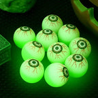 Glowing Eyeball Bouncy Balls with vein details glowing green on a black tabletop