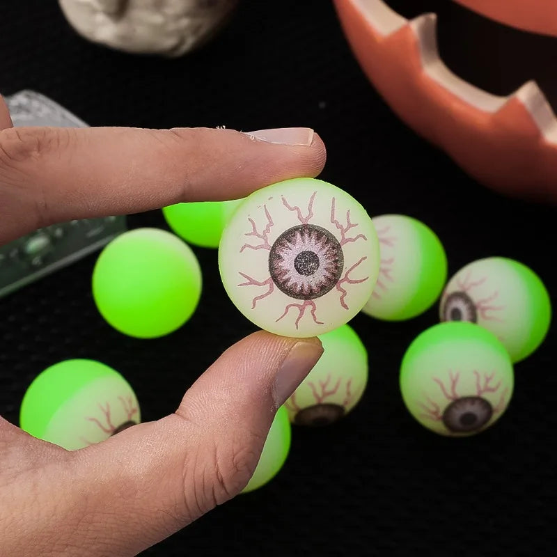 One Glowing Eyeball Bouncy Ball held between two fingers with more balls behind