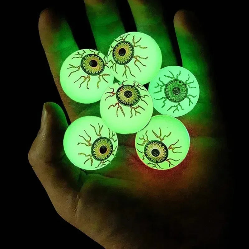 Six green Glowing Eyeball Bouncy Balls resting in an open palm in the dark