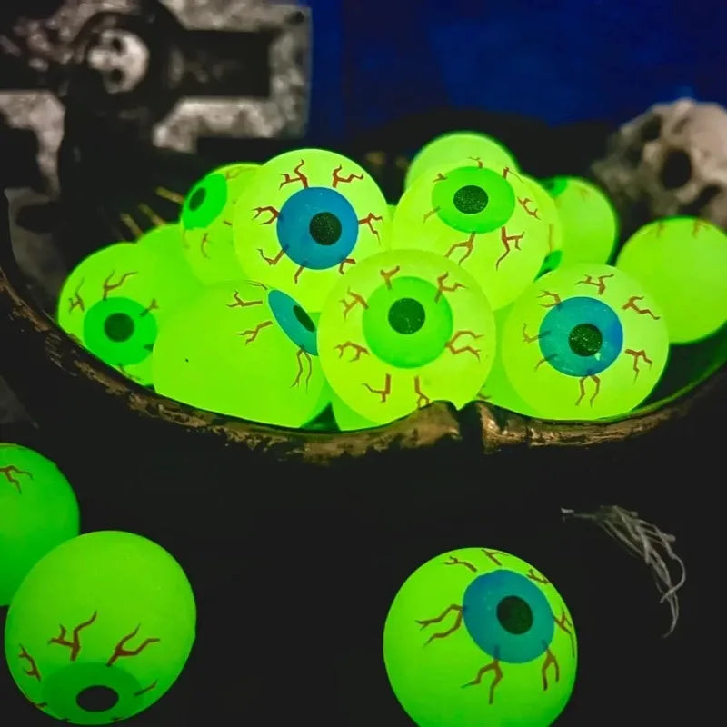 Glowing Eyeball Bouncy Balls with blue and green iris prints in a dark Halloween bowl