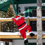 Back view of hanging Santa decoration on a snowy wooden balcony beside a green house.