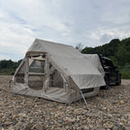 Inflatable Car Camping Tent attached to an SUV on rocky ground, with open doorway and side cover raised