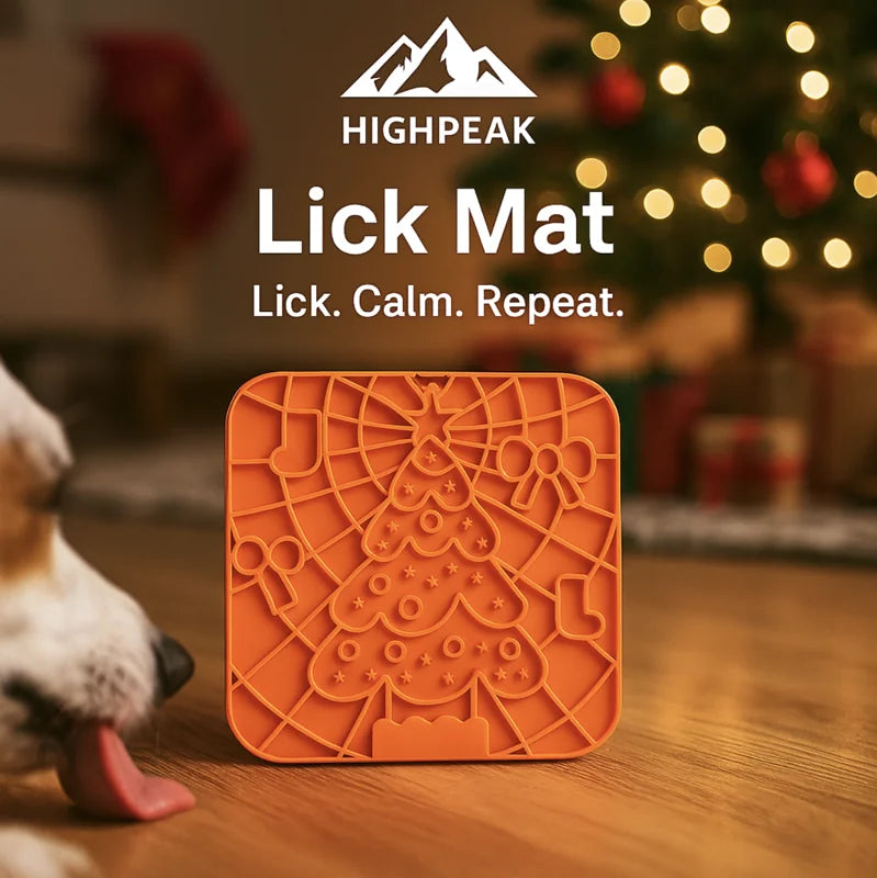 HighPeak Lick Mat in orange with festive grooves beside a dog licking on a hardwood floor near a decorated Christmas tree