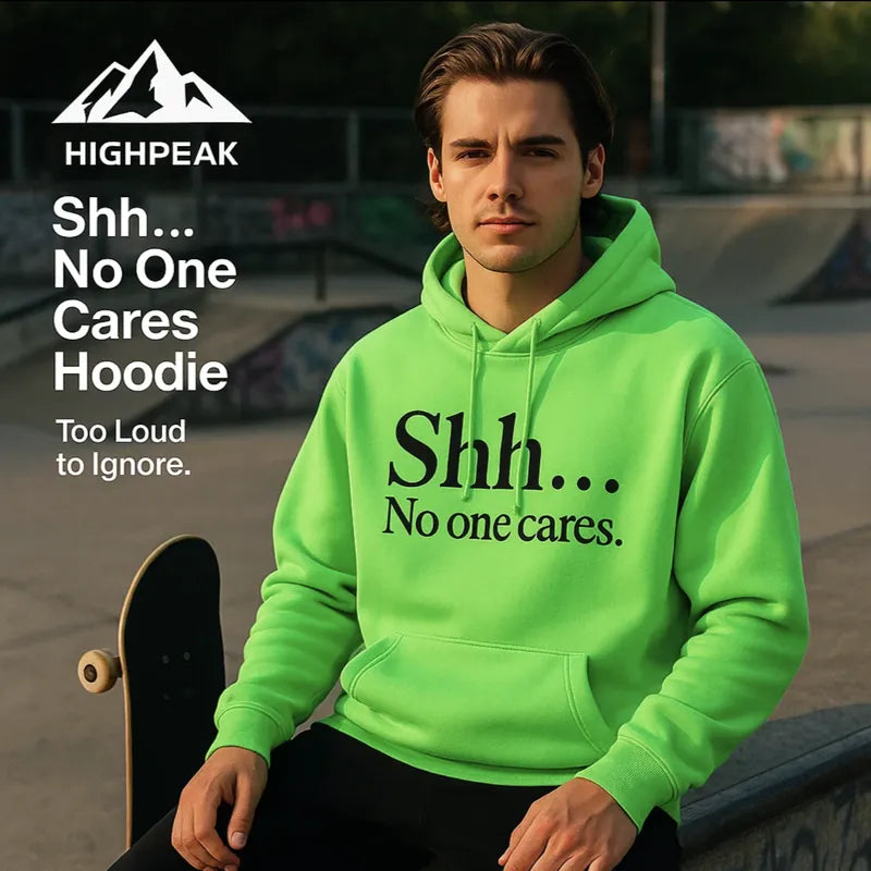 HighPeak Shh... No One Cares Hoodie in bright green with bold black text worn outdoors by a male model with skateboard