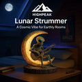 HighPeak Lunar Strummer lamp with glowing crescent moon and alien playing guitar on wooden base in cozy bedroom.