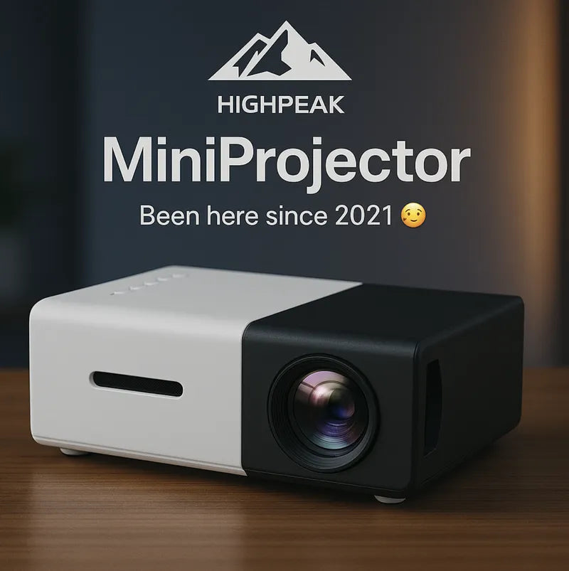 HighPeak MiniProjector in black and white on a wood table, compact design with visible lens and ventilation slot.