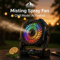 HighPeak Misting Spray Fan with LED mood lights and mist spray on outdoor table at sunset for cooling and charging.