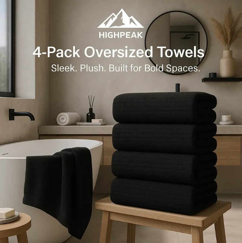HighPeak 4-Pack Oversized Towels in black microfiber stacked on a stool in a modern bathroom setting
