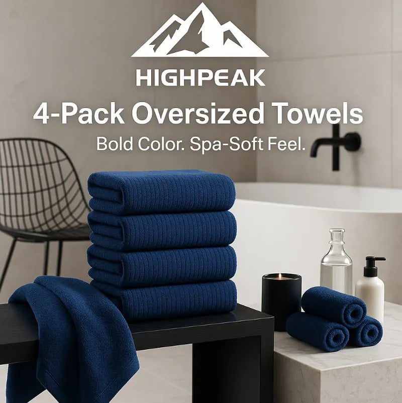 HighPeak 4-Pack Oversized Towels in navy blue stacked in modern bathroom with bath essentials and chair nearby