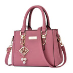 Pebbled Charm Shoulder Purse in pink showing the adjustable strap, handle fittings and hanging charm.
