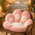 A plush cat paw-shaped cushion in soft pink with white circular pads, displayed on a wooden cane-back chair in a cozy, warmly lit room. The text 'HIGHPEAK Plush Cat Paw Cushion Make Every Seat Adorable' is visible at the top.