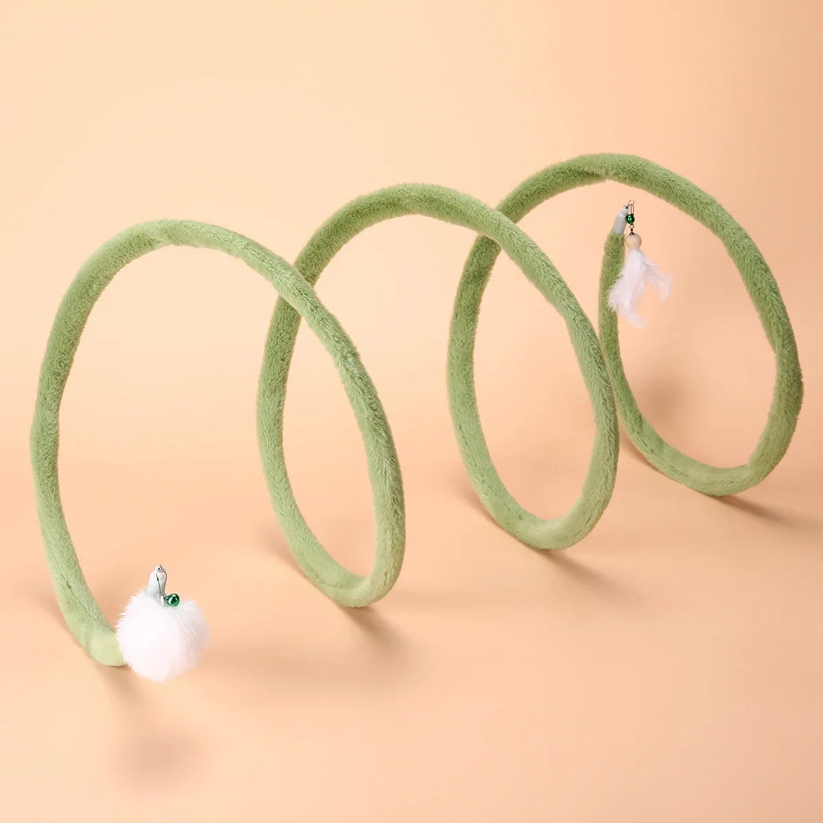 Green Plush Cat Spiral Toy with white pom-pom and feather attachments on a peach background