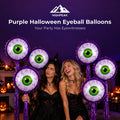 Purple Halloween Eyeball Balloons surrounding two friends in black costumes at a pumpkin-decorated party.