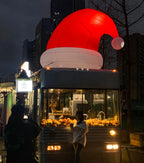 Giant Inflatable Santa Hat illuminated on top of a bus at night