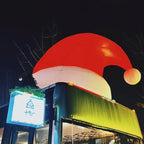 Giant Inflatable Santa Hat glowing above a storefront at night