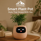 HighPeak Smart Plant Pot in peach with animated face and green plant on wooden table in cozy living room setting