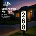 HighPeak Solar Address Sign Light glowing white with black frame mounted on lawn in front of house at dusk