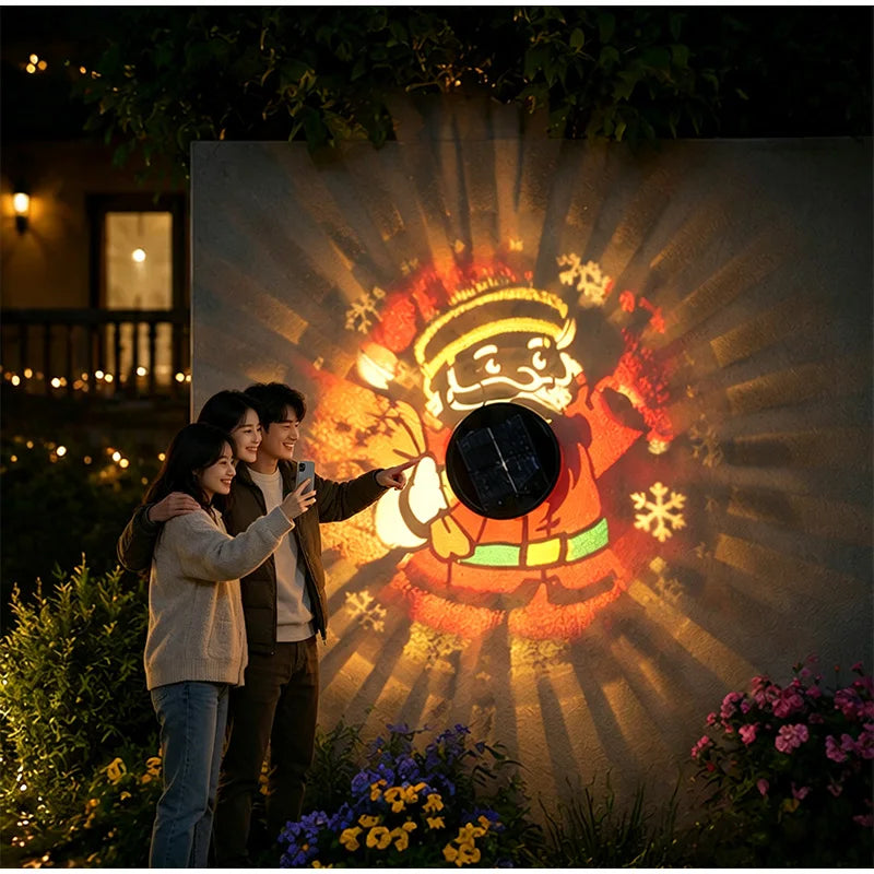 Family taking a photo beside colorful Santa patterns projected onto a flower-lined garden wall